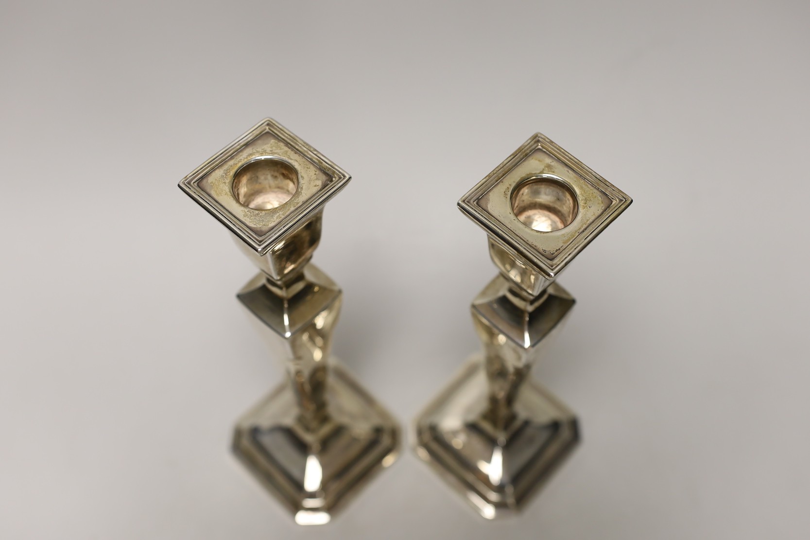 A pair of George V silver mounted candlesticks, London, 1925, height 22.5cm, weighted.